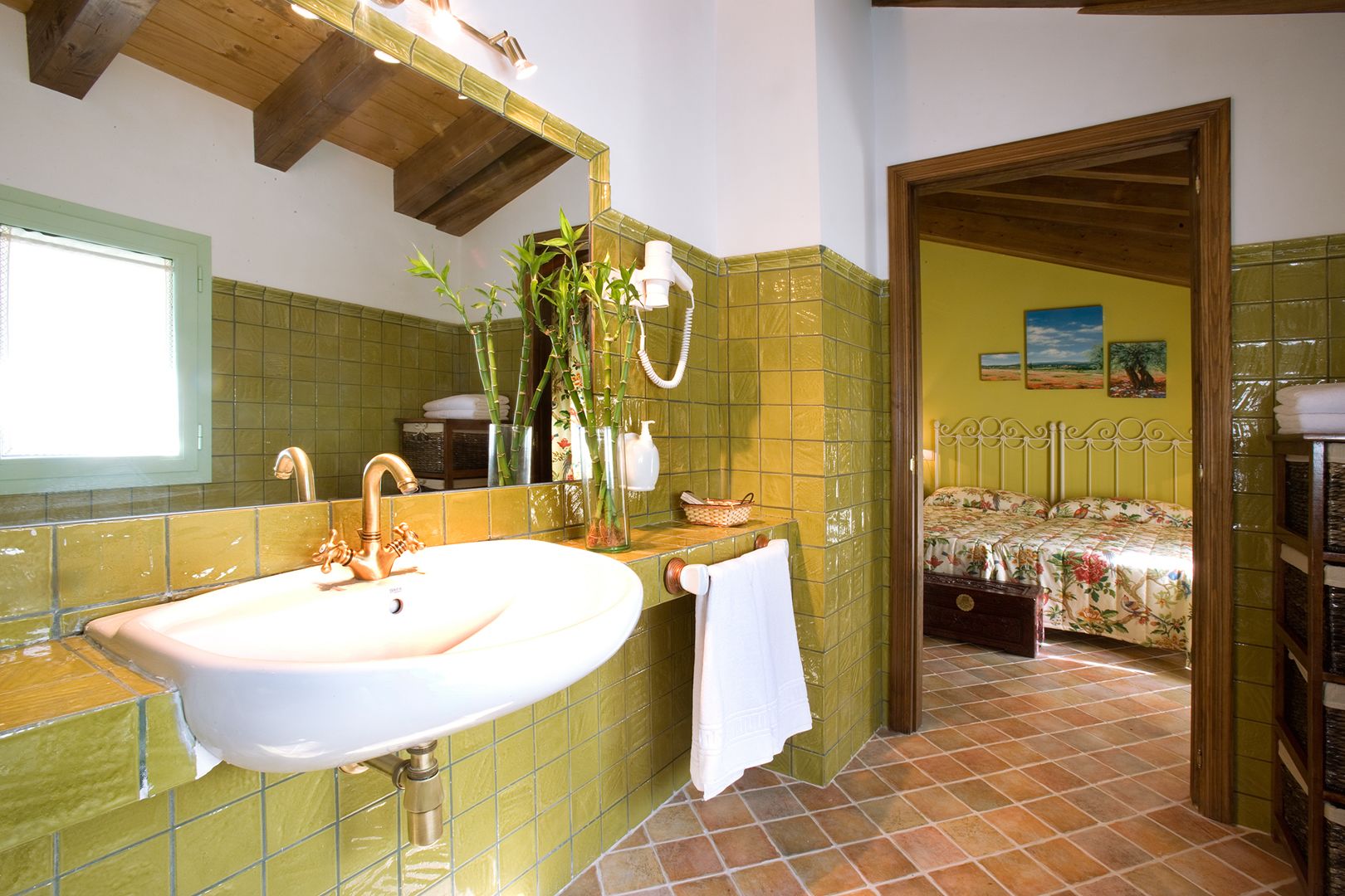 A bathroom with a large sink, bamboo plants, and a mirror.