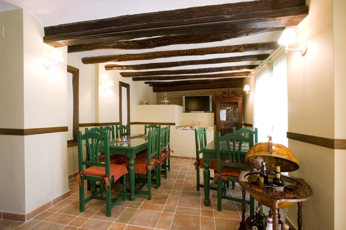 Un comedor con vigas de madera, sillas verdes y un globo terráqueo sobre una mesa.