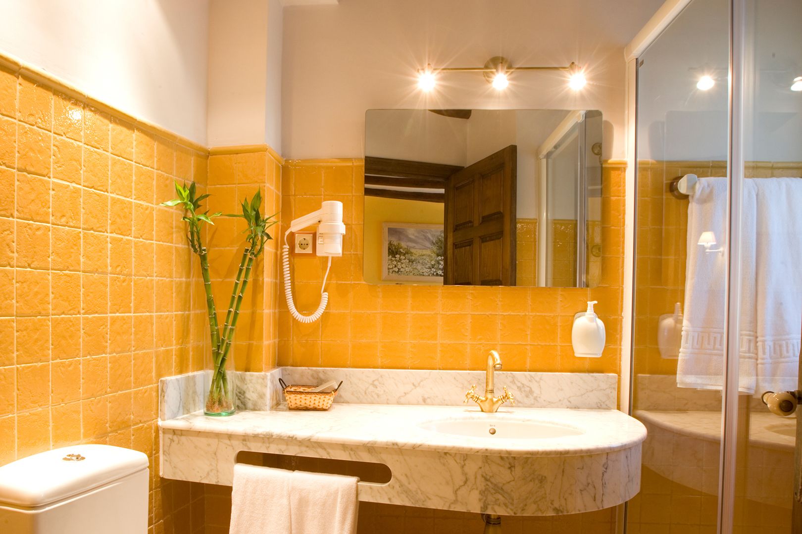 Un baño con lavamanos de mármol, secador de pelo de mano y espejo.