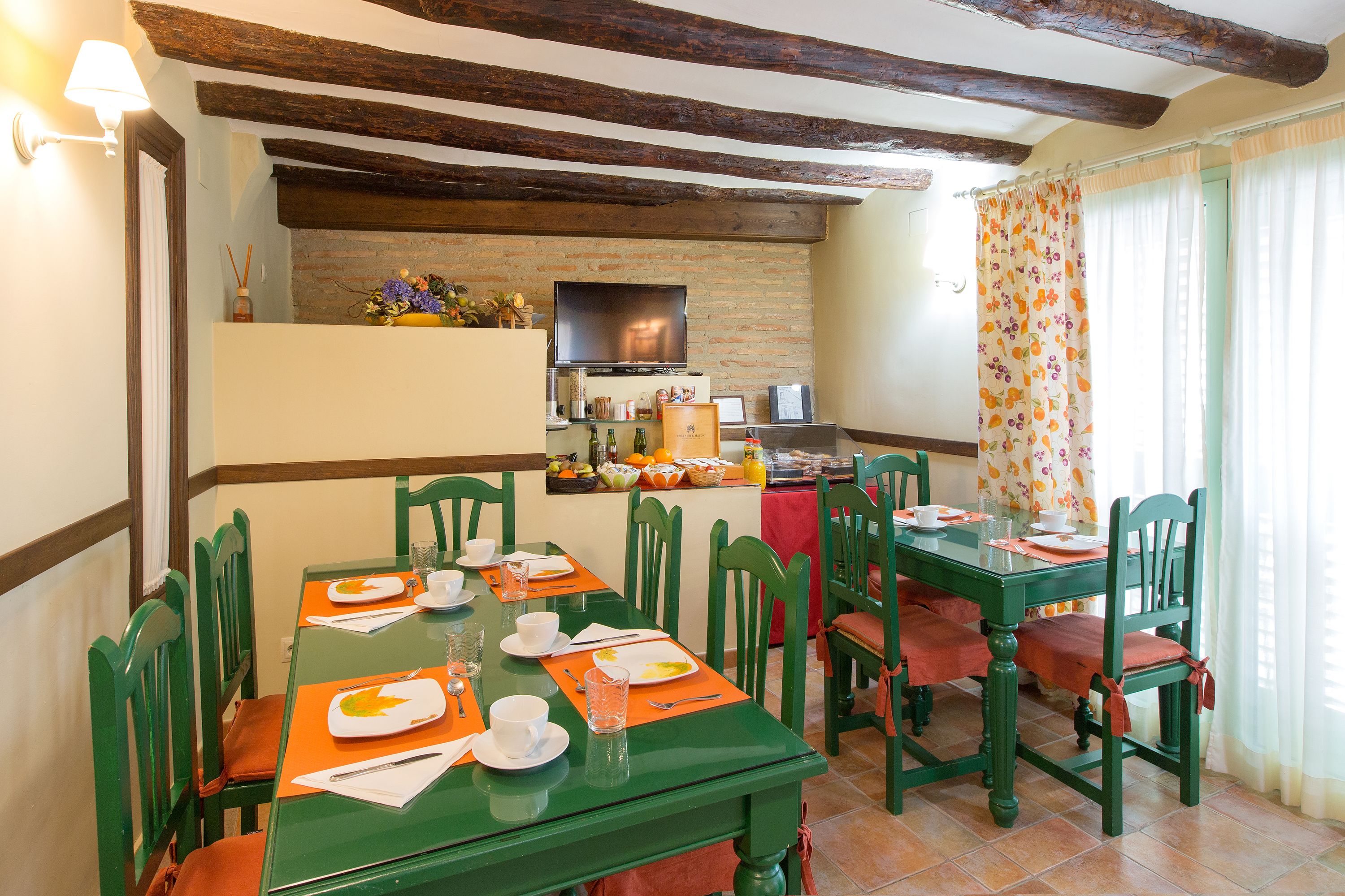 A dining area with a brick wall, wooden beams, and a television.