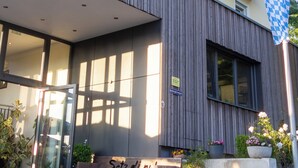 A modern building with a balcony, potted plants, and a bench outside. - Landgasthof Am Sonnenhang (Vohenstrauss)