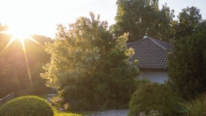 A house with a tiled roof, surrounded by lush greenery and a paved pathway. - Landgasthof Am Sonnenhang (Vohenstrauss)