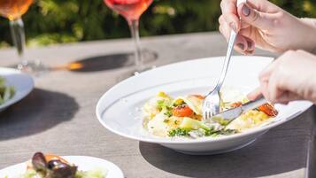 A dining table with plates of food and glasses of wine.