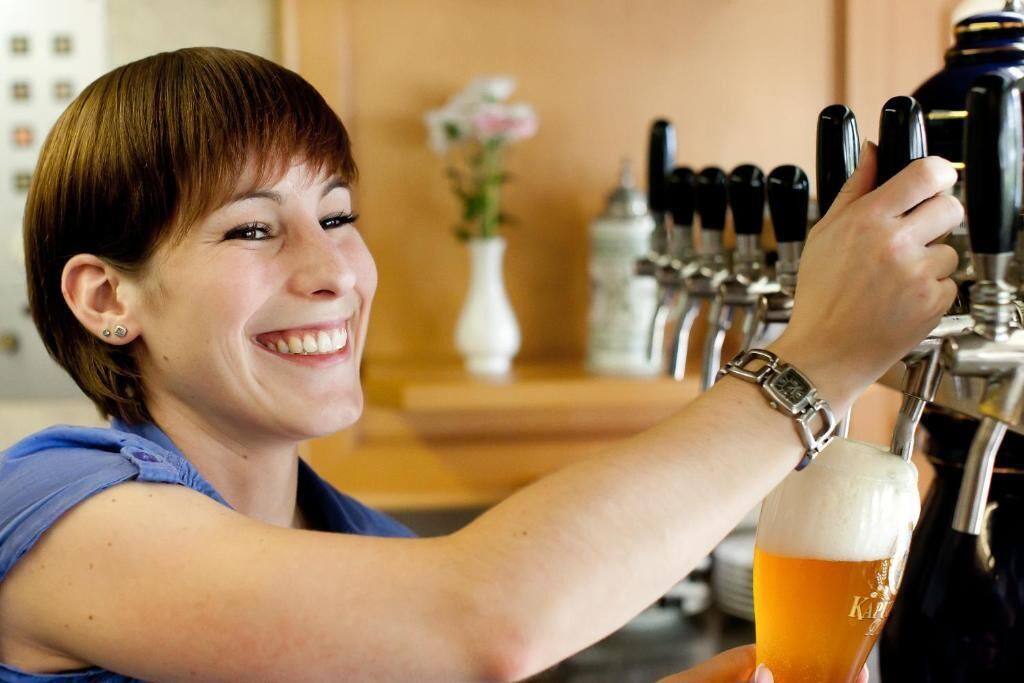 A person pouring beer from a tap into a glass.