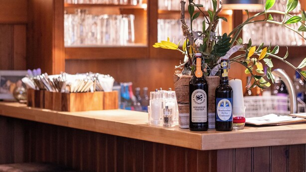 A bar area with wooden shelves, hanging pendant lights, and a counter with bottles and glasses. - Landgasthof Am Sonnenhang (Vohenstrauss)