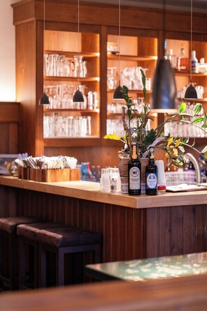 A bar area with wooden shelves, hanging pendant lights, and a counter with bottles and glasses. - Landgasthof Am Sonnenhang (Vohenstrauss)