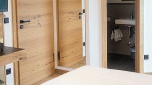 A modern bedroom with a wooden wardrobe, a bedside table, and a bathroom visible through an open door. - Landgasthof Am Sonnenhang (Vohenstrauss)