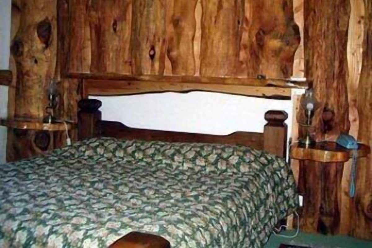 Una cama con cabecera de madera y colcha estampada.