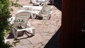 Una casa con patio, arredato con poltrone da relax bianche e pavimento in pietra.