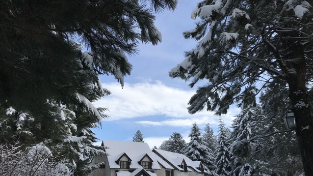 Una casa ricoperta di neve con tetto simmetrico e un portico.