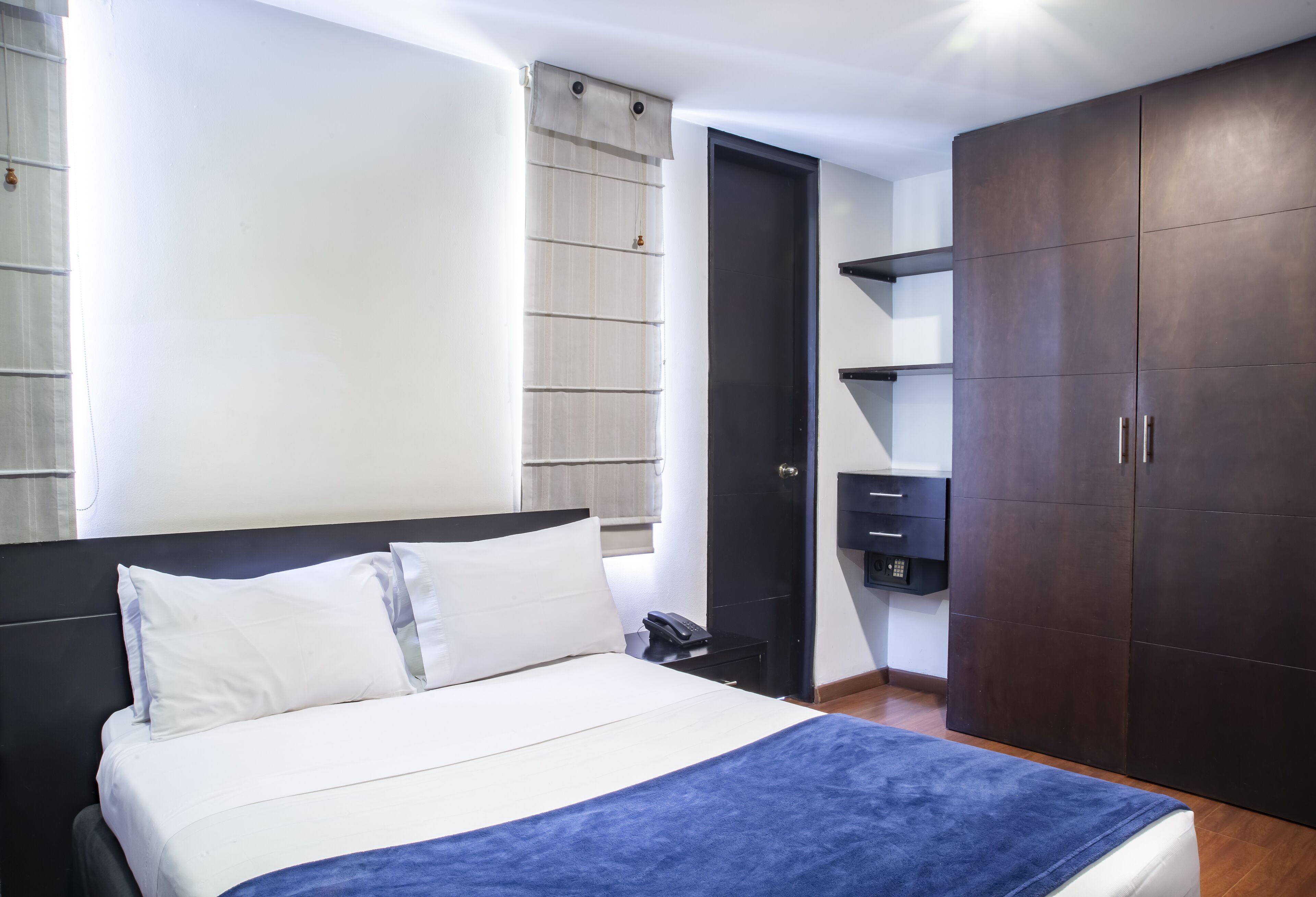 A bedroom with a bed, a wardrobe, a nightstand, and a door.