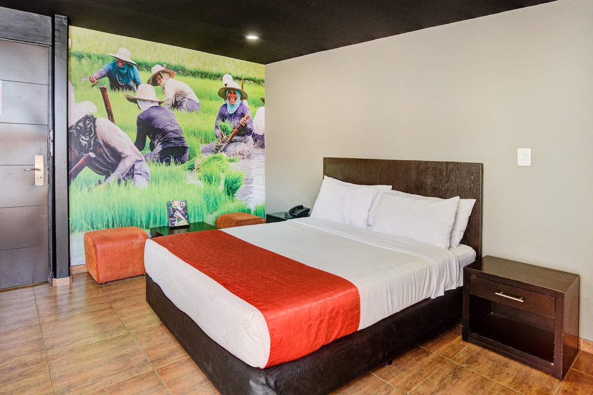 Camera da letto con un letto grande, un comodino, un pavimento in legno e un affresco raffigurante persone al lavoro in un campo.