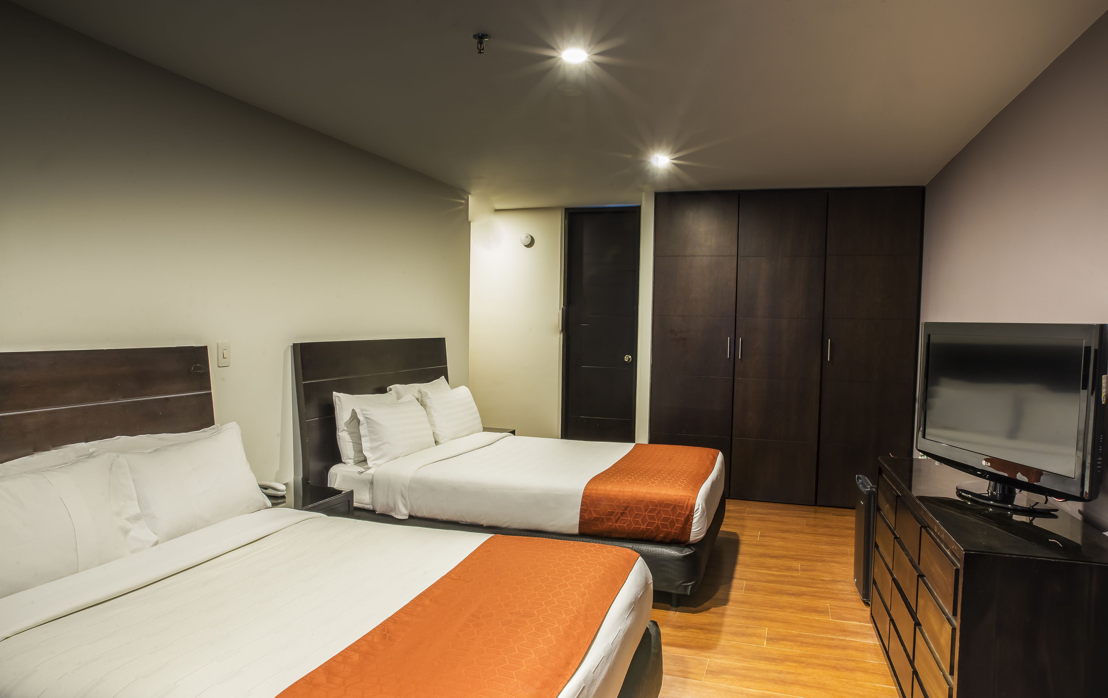 Een hotelkamer met twee bedden, een televisie en een kledingkast.