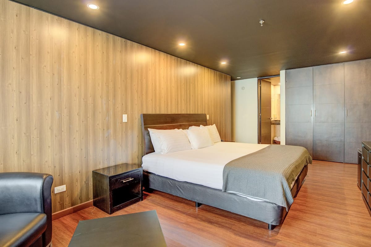 Una camera da letto moderna con una parete in legno, un letto grande, un comodino, una sedia e un armadio.