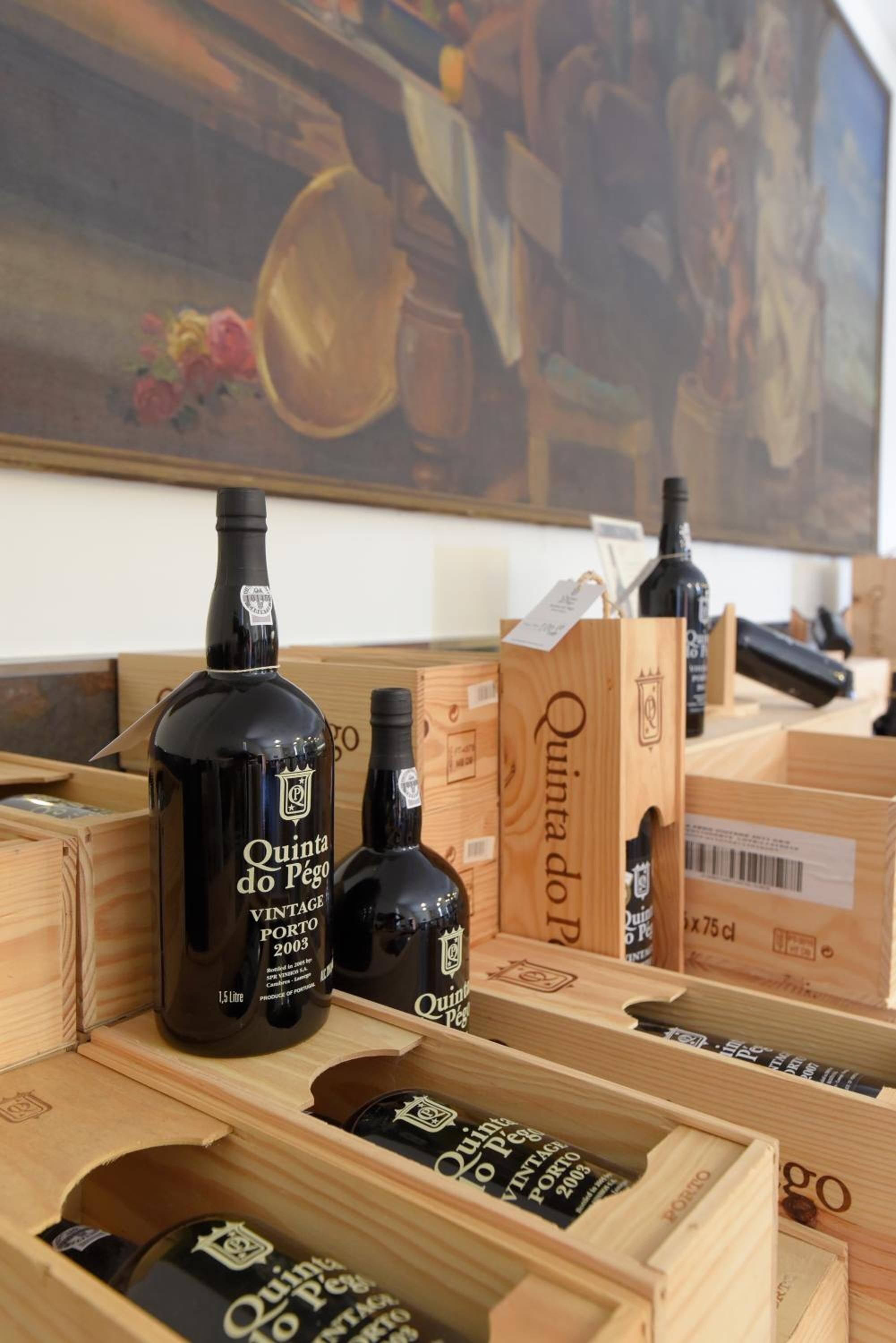 A selection of vintage Porto wine bottles in wooden crates, with a vintage painting in the background.