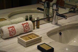 A bathroom with a marble sink, a towel, and several bottles of toiletries.
