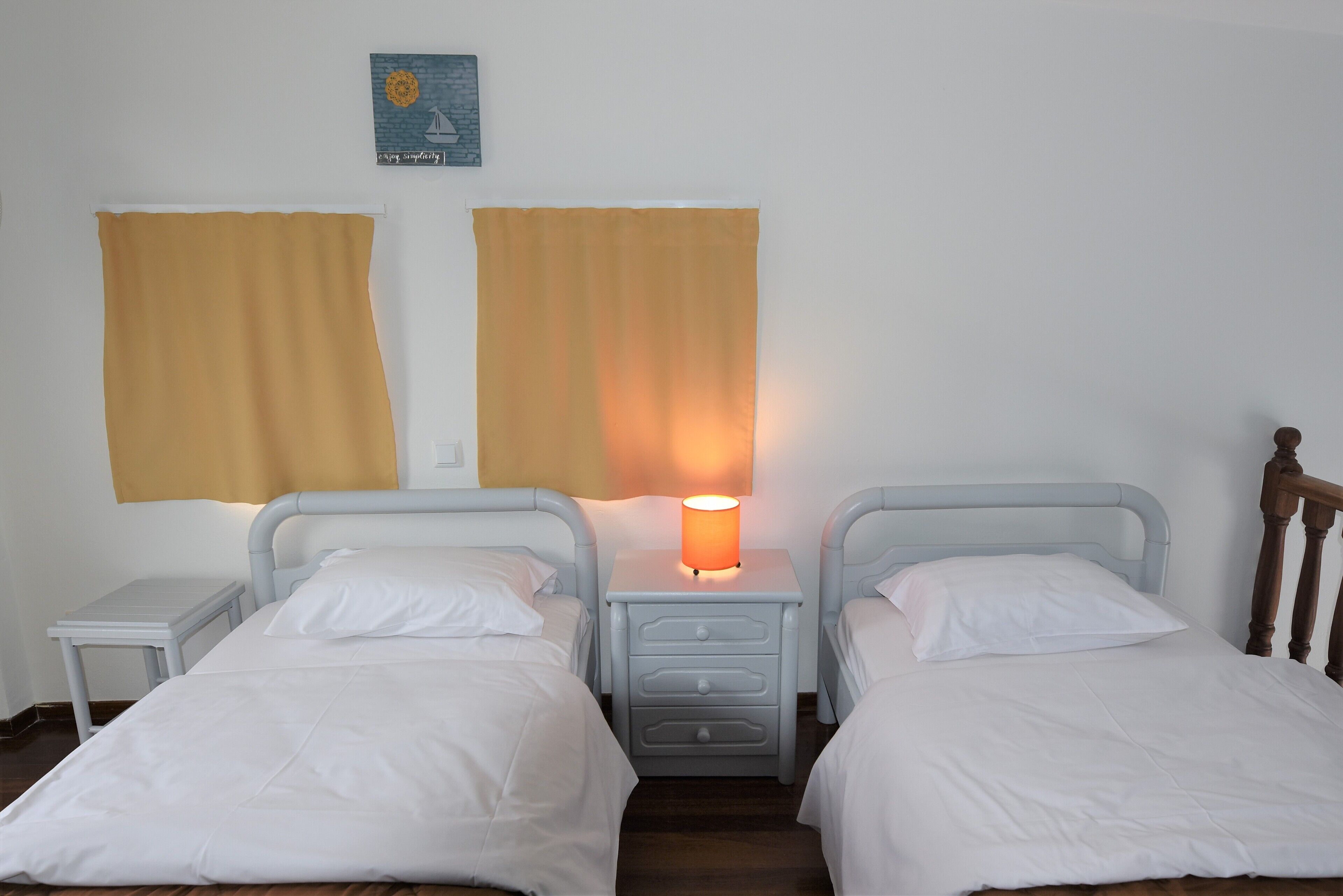 A twin room with two beds, a nightstand with a lamp, and a wall-mounted artwork.