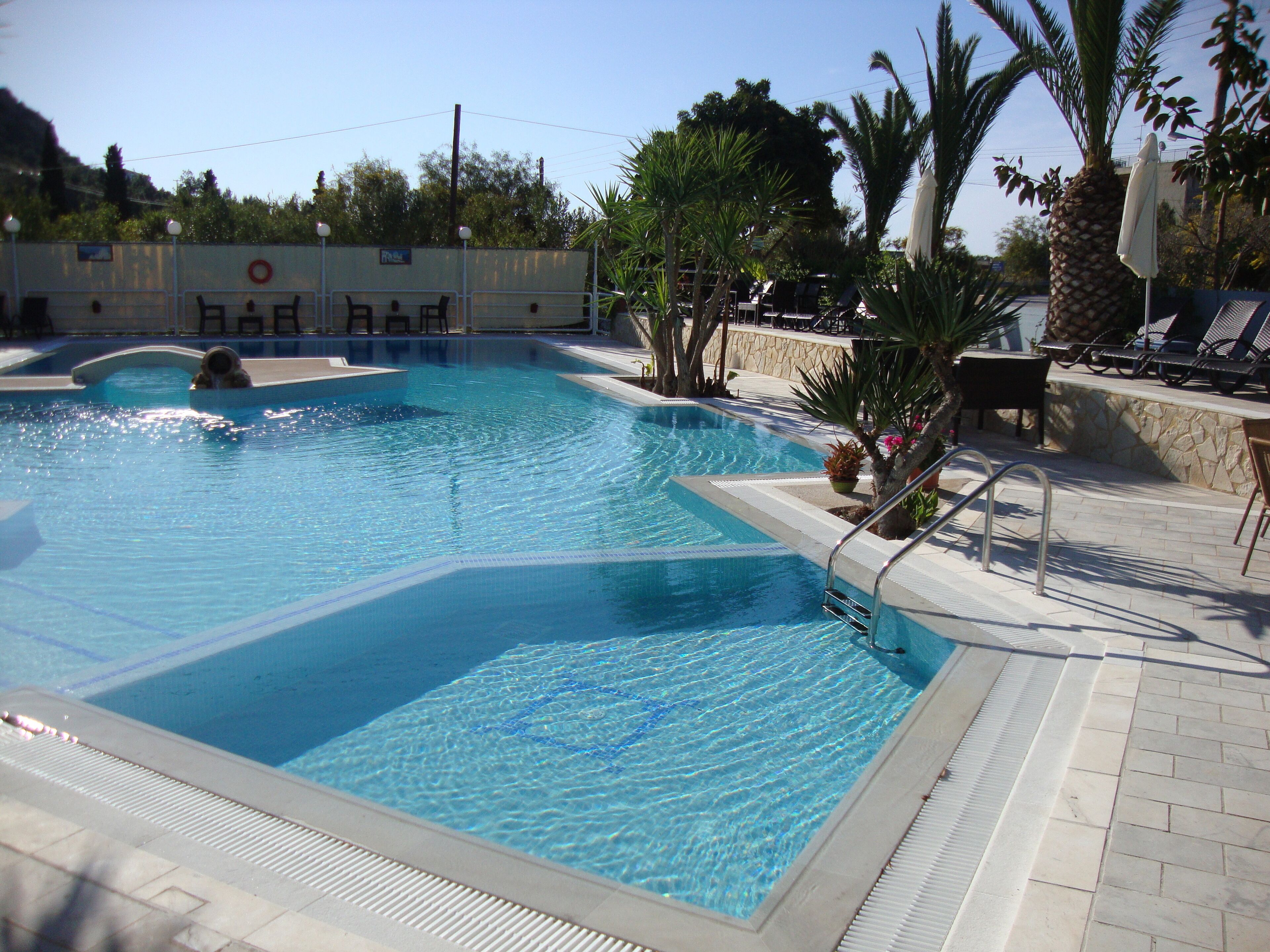 A swimming pool with a diving board and lounge chairs.