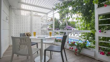 A covered patio with a pool view, white lattice partition, and outdoor seating.
