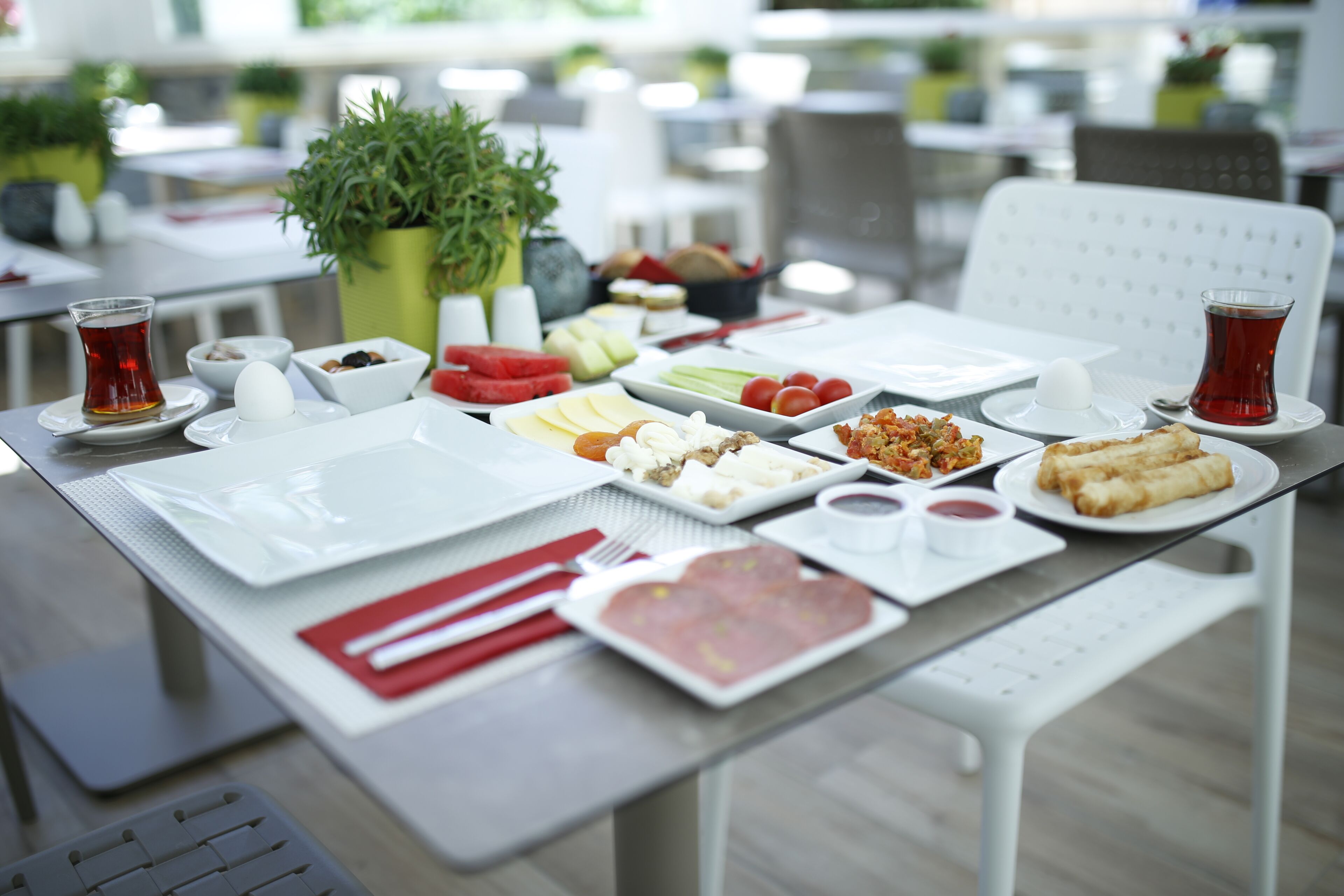 A dining table set with various dishes, utensils, and a cup of tea.