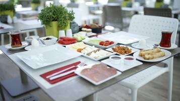 A dining table set with various dishes, utensils, and a cup of tea.