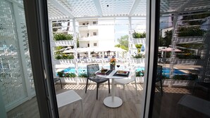 A modern outdoor seating area with a pool, white furniture, and a view of a multi-story building. - Ascot Hotel Buyukada (Adalar)