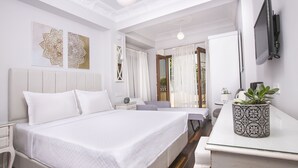 A hotel room with a large bed, bedside tables, a desk, a potted plant, and a TV mounted on the wall. - Ascot Hotel Buyukada (Adalar)