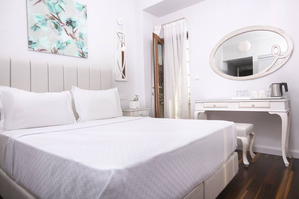 A neatly arranged bedroom with a bed, bedside table, and a desk with a mirror.