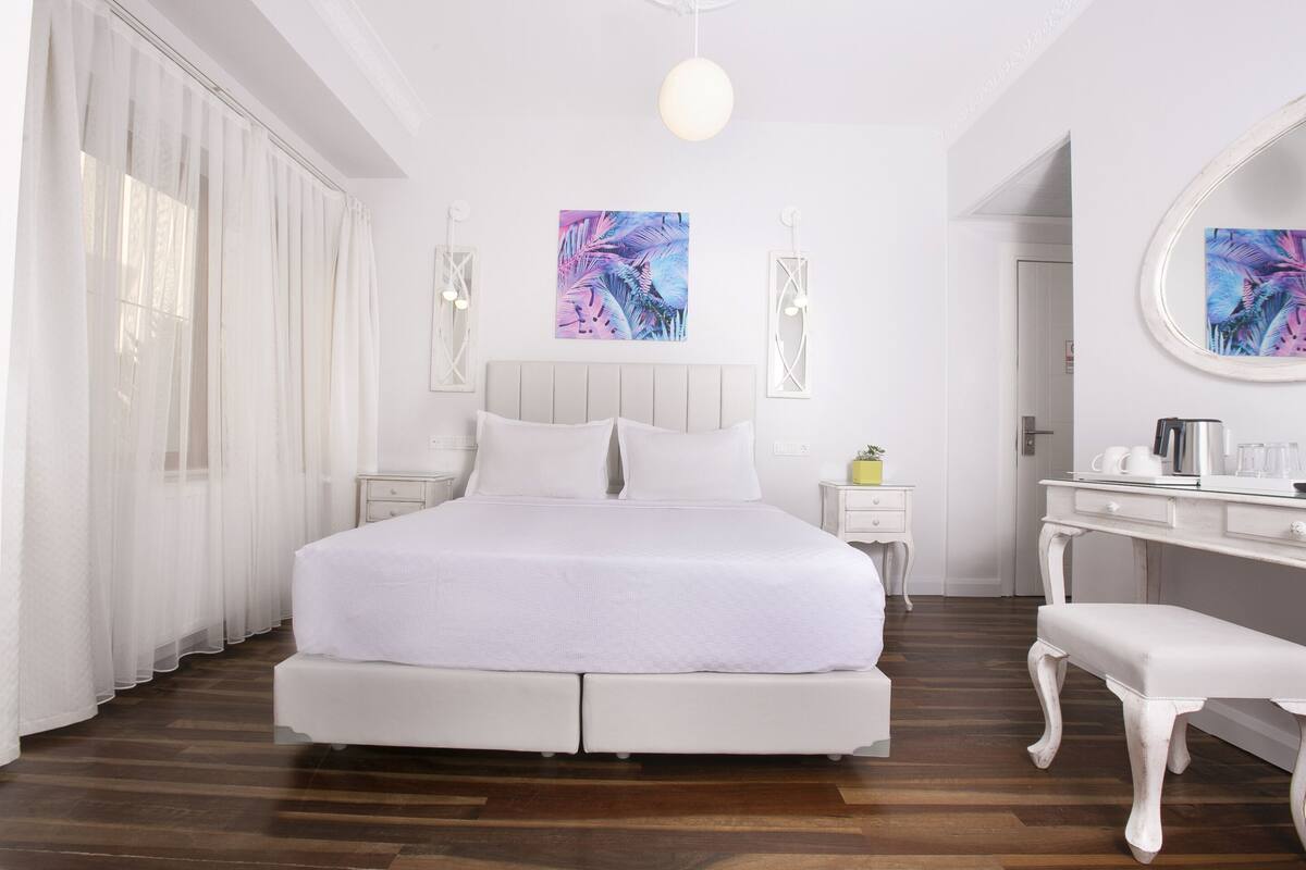 A modern bedroom with a large bed, bedside tables, a bench, and artwork on the walls.