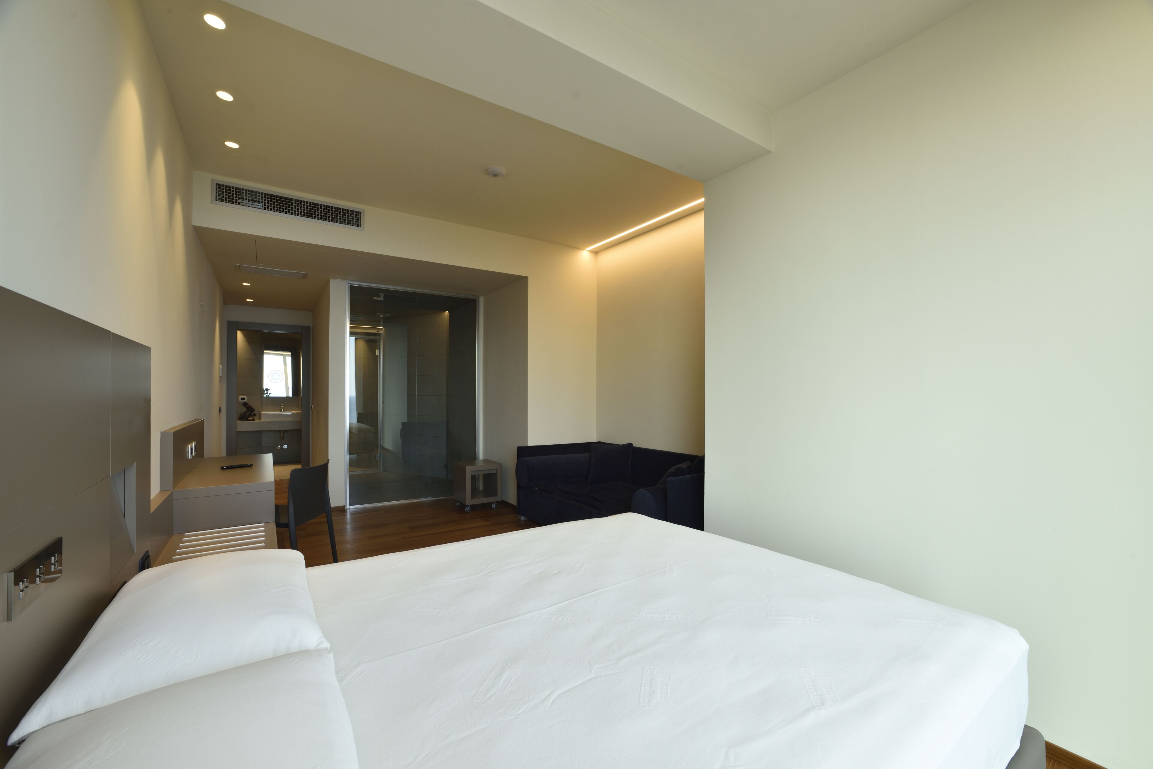 Een moderne hotelkamer met een groot bed, een klein bureau en een zithoek.