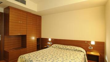 Ein Schlafzimmer mit einem großen Bett, einem Holzschrank, Nachttischen und einem Beistelltisch.
