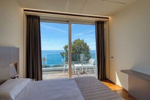 A bedroom with a large bed, a view of the sea, and a balcony with outdoor furniture. - Hotel Le Roi (Varazze)