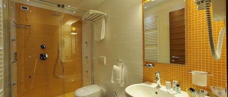 Un baño con ducha de vidrio, inodoro, bidé y lavabo con espejo.