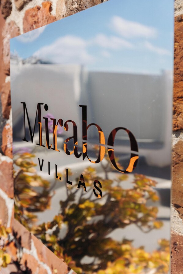 Een bord met de tekst 'Mirabé Villas' voor een achtergrond van een bakstenen muur.