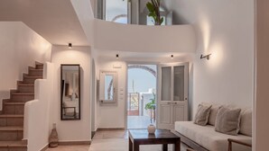 A modern interior with a staircase, a sofa, a coffee table, and a view through an open door.