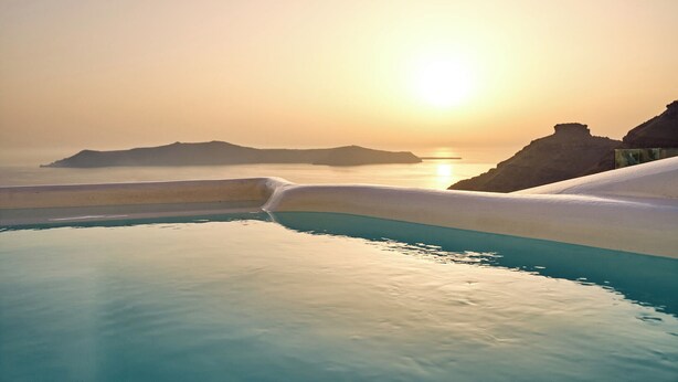A pool with clear blue water and a sunset view.