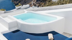 A hot tub with a view of the sea and cliffs.