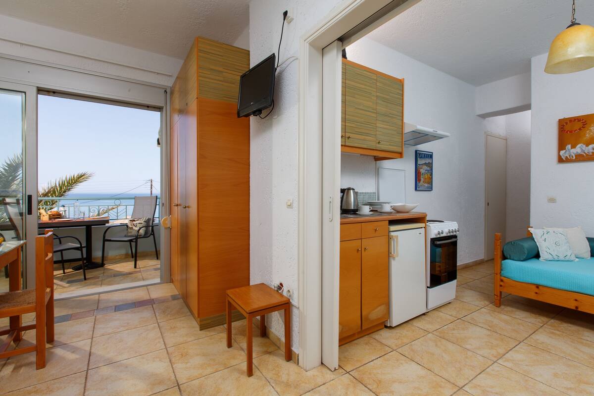 Ein kompakter Wohnraum mit Küchenzeile, Essbereich und Balkon mit Blick.