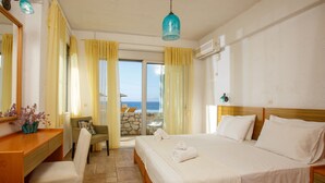 Une chambre d’hôtel avec un lit, un bureau, une chaise et une vue sur la mer.