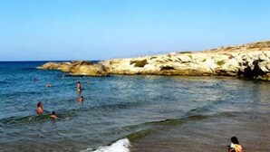 Une plage à l’eau claire, bordée de falaises rocheuses.