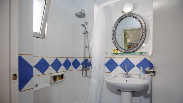 A bathroom with a shower, toilet, sink, and mirror. - Romantica Beach Villas (Hersonissos)