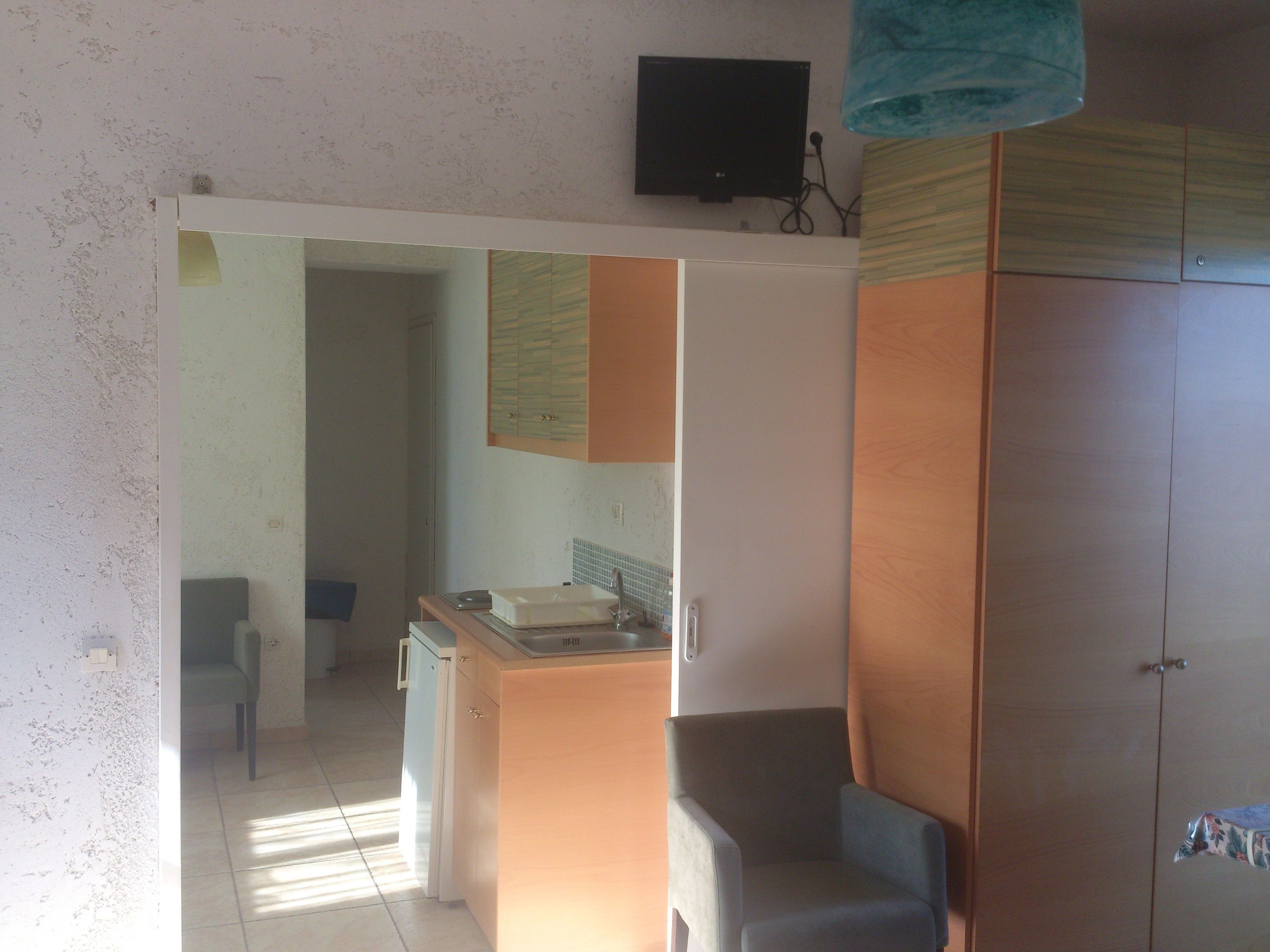 A compact kitchen with a refrigerator, sink, and cabinets.