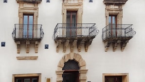 A building with three balconies, a central archway, and two doors. - Hotel Palazzo Zuppello (Augusta)