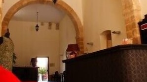 A room with a large arched doorway, a black ottoman, and a red sofa. - Hotel Palazzo Zuppello (Augusta)