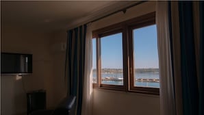 A room with a large window offering a view of a body of water and a dock. - Hotel Palazzo Zuppello (Augusta)