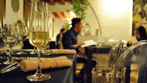 A dining table with a glass of white wine, a menu, and a knife. - Hotel Palazzo Zuppello (Augusta)