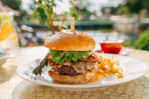Un hamburger servi sur une assiette, avec un pain, de la laitue, du bacon et du fromage.