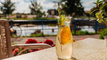 A clear glass bottle with a slice of orange and a sprig of herb on a table.