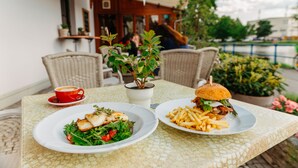 A table with two plates of food, a red cup, and a potted plant. - Hotel Klika (Ceske Budejovice)