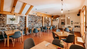 A restaurant with wooden tables and chairs, stone walls, and hanging light fixtures. - Hotel Klika (Ceske Budejovice)